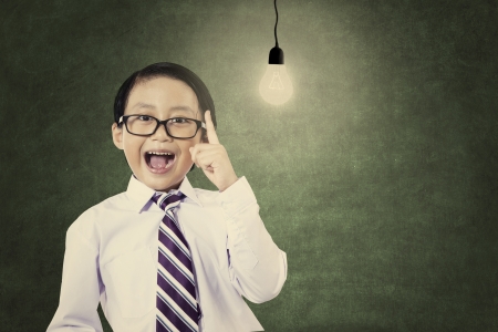 Asian genius schoolboy with light bulb shot in a classroomの写真素材