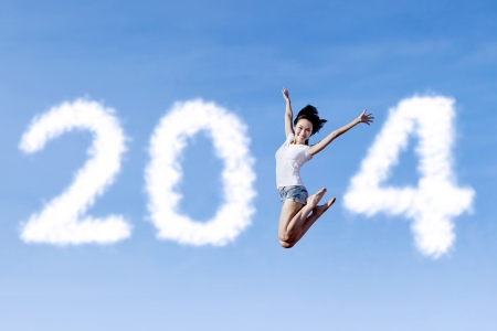 Excited asian woman is jumping with new year 2014 on the clear skyの写真素材