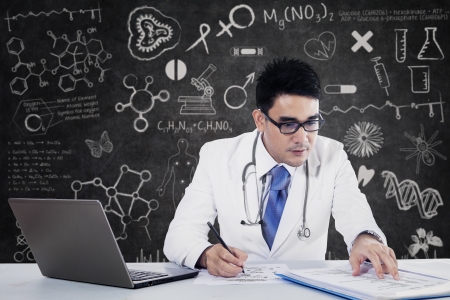 Young doctor writing notes with a notebook at the deskの写真素材