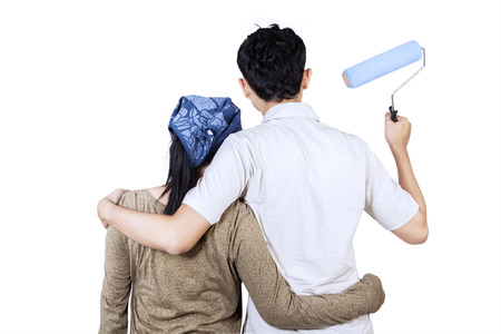 Rear view of young couple looking wall and ready to painting the wall. isolated on whiteの写真素材
