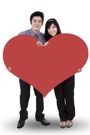 Couple in love holding a big red heart isolated on white backgroundの写真素材