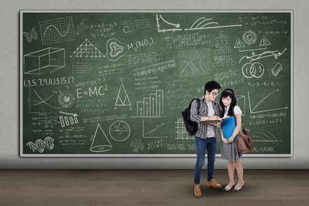 Happy college students reading a book in classroomの写真素材