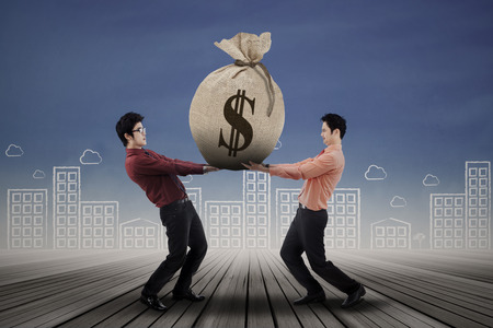 Two business people carrying a money bag with US dollar signの写真素材