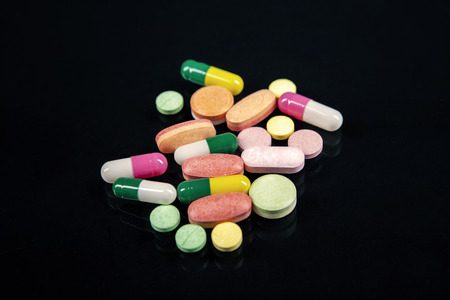 Closeup of many colorful pills isolated on black 