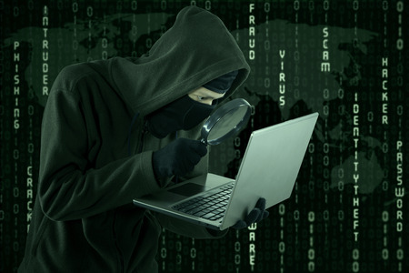 Portrait of hacker looking for user information by using magnifying glass