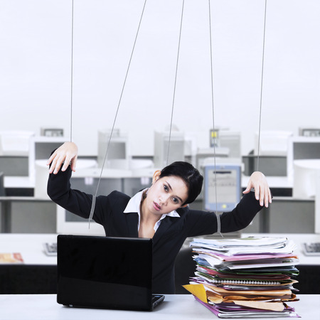 Portrait of businesswoman working at office controlled by stringsの写真素材