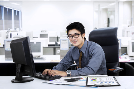 Portrait of young manager working at office while typing on keyboardの写真素材