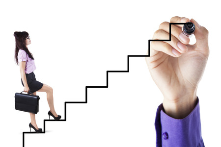 Businesswoman stepping up on stairs to gain her success with a hand drawing the stairsの写真素材