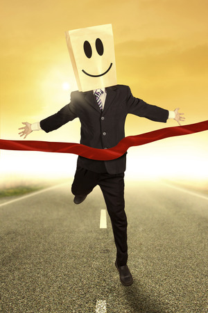 Businessman with cardboard head winning a race competitionの写真素材
