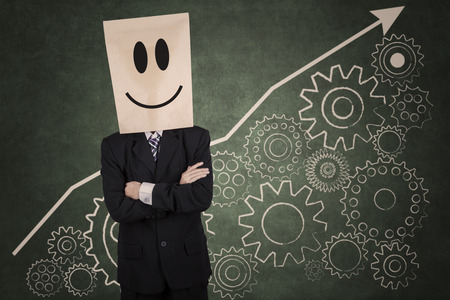 Successful businessman with carton head and financial graph, gear, on the wallの写真素材