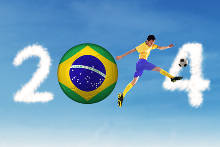 A Brazilian soccer player kicking the ball on the clouds of 2014の写真素材