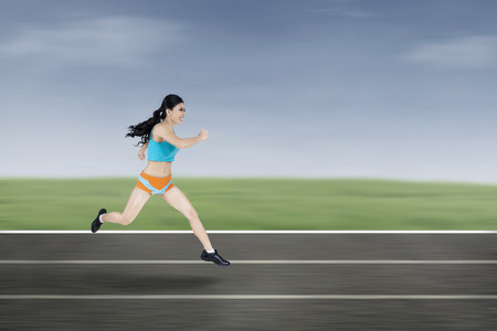 Young athletic woman running on a trackの写真素材