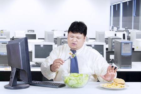 Overweight businessman avoid junk food and choose to eat saladの写真素材