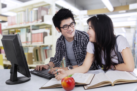 Two asian college students studying together at libraryの写真素材