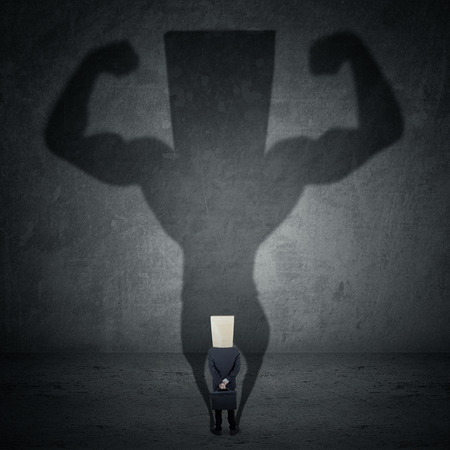 Business man casting a shadow of an athlete - business and career strength conceptの写真素材