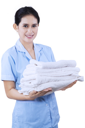 Smiling young cleaning lady holding towels isolated on white backgroundの写真素材