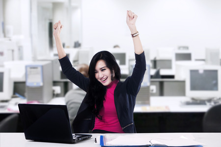 Successful asian businesswoman with arms up - shot in the officeの写真素材