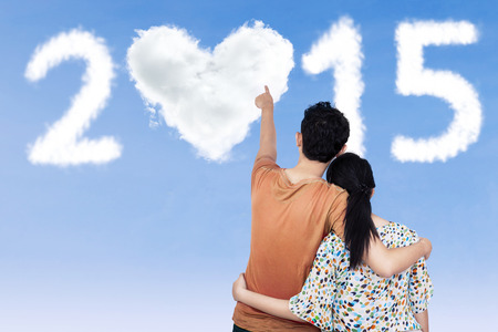 Rear view couple embracing and look at heart shaped cloud number 2015の写真素材