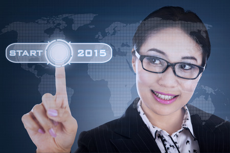 Young hispanic woman pushing start button on a virtual screen to future 2015