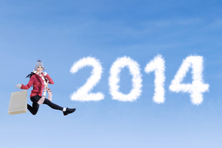 Asian woman jumping beside on the word 2014 on the blue skyの写真素材