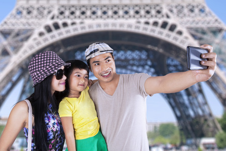 Three member of asian tourist take self portrait together in eiffel towerの写真素材