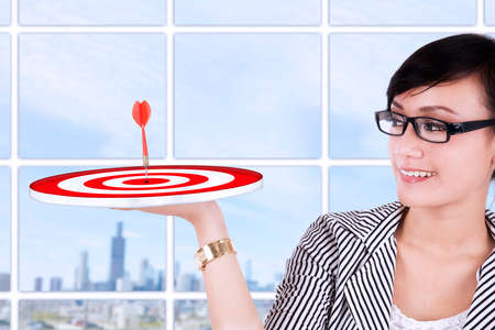 Beautiful asian businesswoman holding a target at modern officeの写真素材