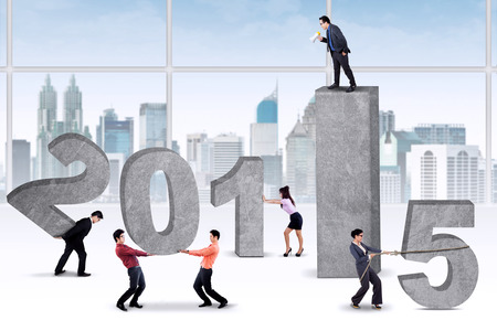 Bossy businessman commanding his employees to arrange number 2015の写真素材