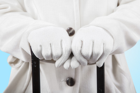 Closeup of woman hands in winter gloves and warm clothes, holding a luggage handgrip