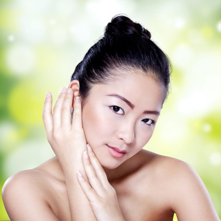 Portrait of young chinese girl with beauty perfect skin looking at the camera against bokeh light backgroundの写真素材