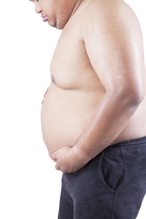 Closeup of overweight person holding his abdomen, isolated on white backgroundの写真素材