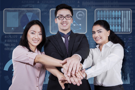 Portrait of young multicultural businesspeople smiling at the camera while joining hands