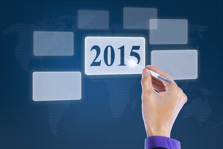 Closeup of hand using stylus to press a virtual button with number 2015 on the high tech screenの写真素材