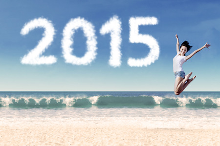 Joyful woman jumping at beach to celebrate new year of 2015の写真素材