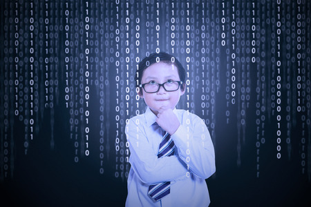 Portrait of little boy in front of a computer screen with binary code on it Portrait of little boy in front of a computer screen with binary code on it