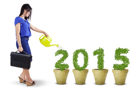 Portrait of businesswoman pouring water into the trees shaped number 2015
