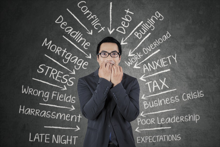 Young business person biting his nail with scared expression, facing many pressureの写真素材