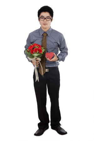 Full length of yougn chinese man holding a bouquet of roses and gift to celebrate valentine's dayの写真素材