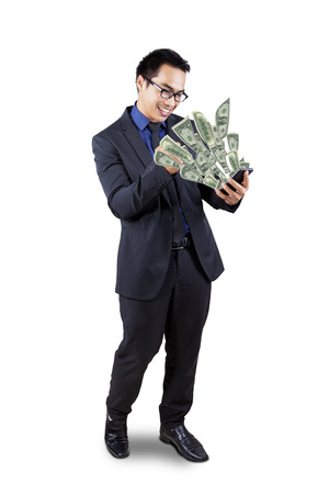 Cheerful businessman looking at dollar cash coming out from his cellphone, isolated on whiteの写真素材
