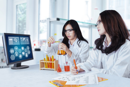 Portrait of two beautiful schoolgirls doing experiment together in the laboratory