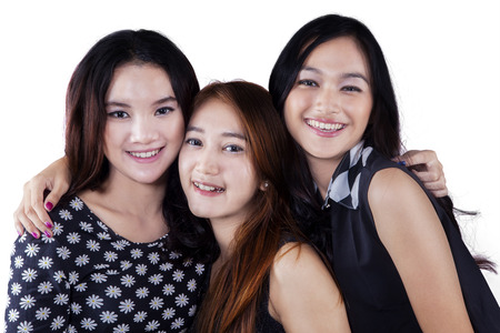 Portrait of friendly teenage girls looking and smiling at the camera in the studio, isolated on whiteの写真素材