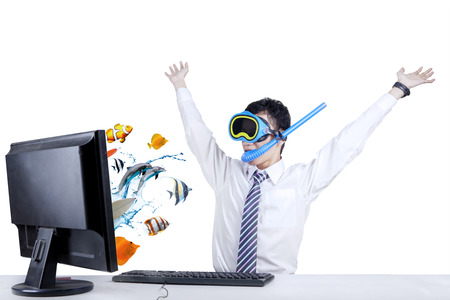 Shocked businessman with snorkeling mask looking at fishes coming out from computer screenの写真素材