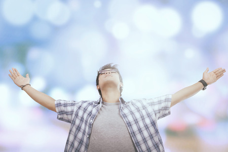 Portrait of young casual man enjoying freedom, shot against a light glitter backgroundの写真素材