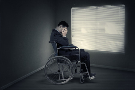 Portrait of disabled entrepreneur looks sad and sitting in wheelchair near the windowの写真素材