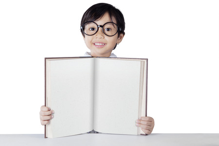 Portrait of a cute student with glasses shows empty book on the camera, isolated on whiteの写真素材