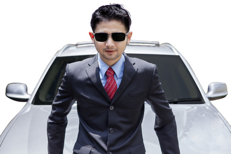 Portrait of young man with formal suit and sunglasses, standing near the expensive new carの写真素材