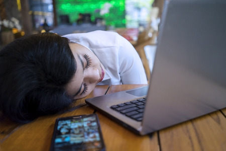 Young businesswoman take a rest in the cafe and sleeping with laptop on the tableの写真素材