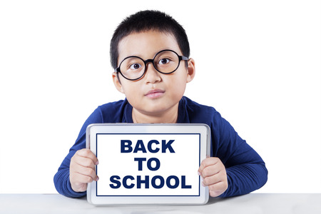 Little boy wearing glasses and showing a text of back to school with a digital tablet, isolated on...