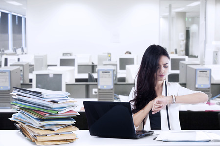 Overworked businesswoman looking at a clock. shoot at workplace