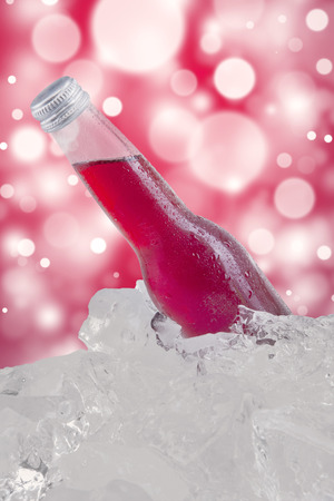 Fresh lager in the bottle with red color and dew on the cold ice cube. Shot with bokeh backgroundの写真素材