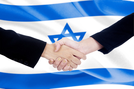 Two politicians in business suit, shaking hands in front of israel flag backgroundの写真素材
